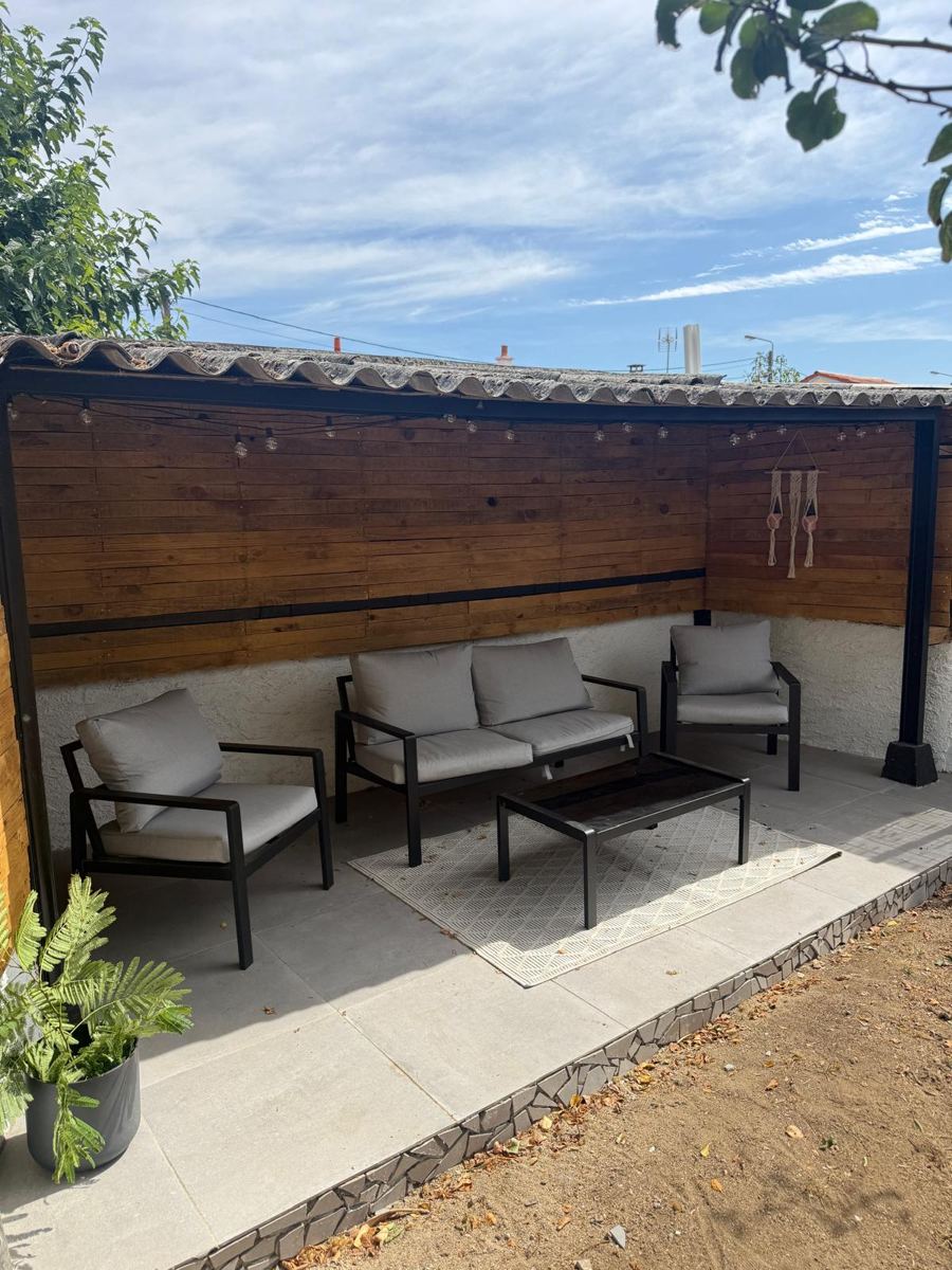 Après : terrasse couverte dallée avec bardage bois, salon de jardin et guirlande lumineuse